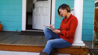 woman drawing while sitting on front porch