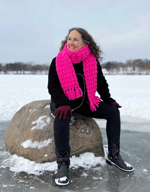 brenda sitting outside in the snow wearing the moss stitch scarf