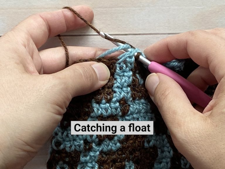 hands crocheting blue and brown yarn demonstrating catching a float