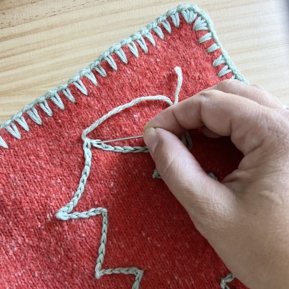 a hand finishing surface crochet on a Christmas tree outline on a crochet potholder