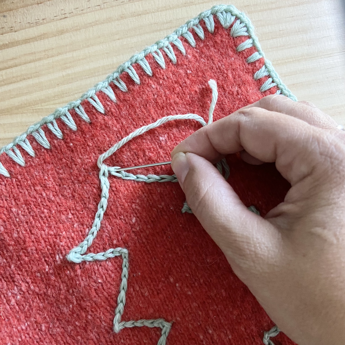 a hand finishing surface crochet on a Christmas tree outline on a crochet potholder