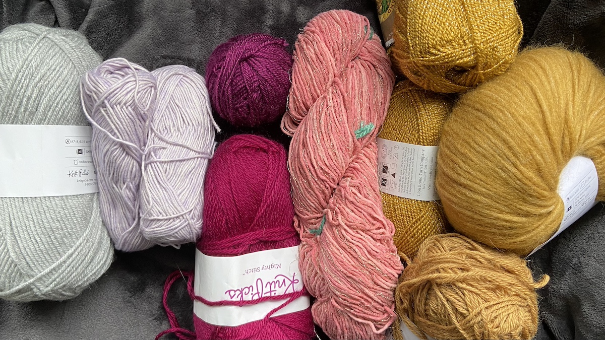 a pile of yarn in various colors sitting atop a fleece blanket