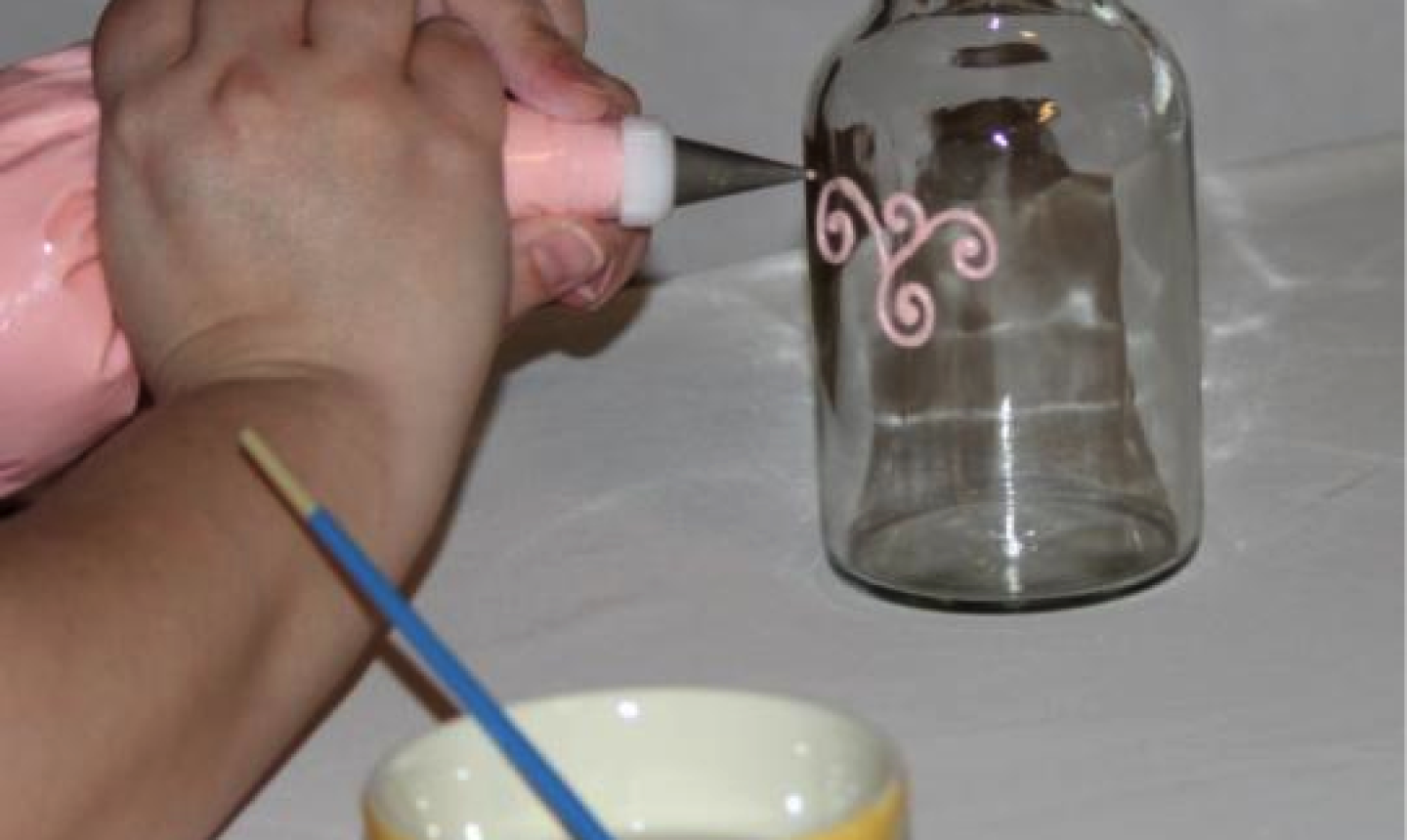 Hands Demonstrating Filigree Piping on Glass Bottle