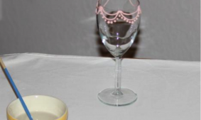 Icing Piped on a Wine Glass Next to Bowl of Water