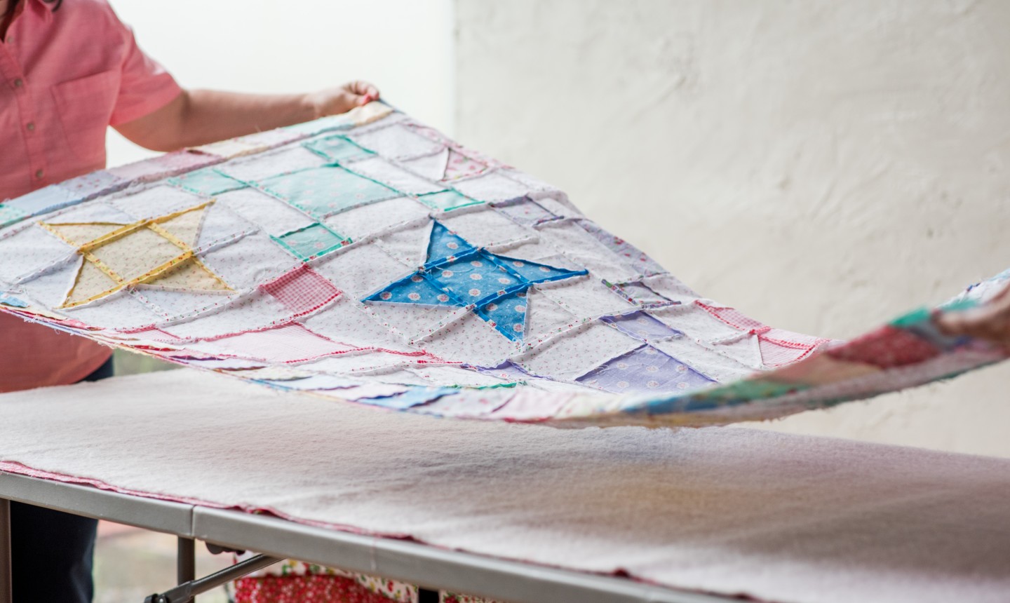 woman laying out quilt top