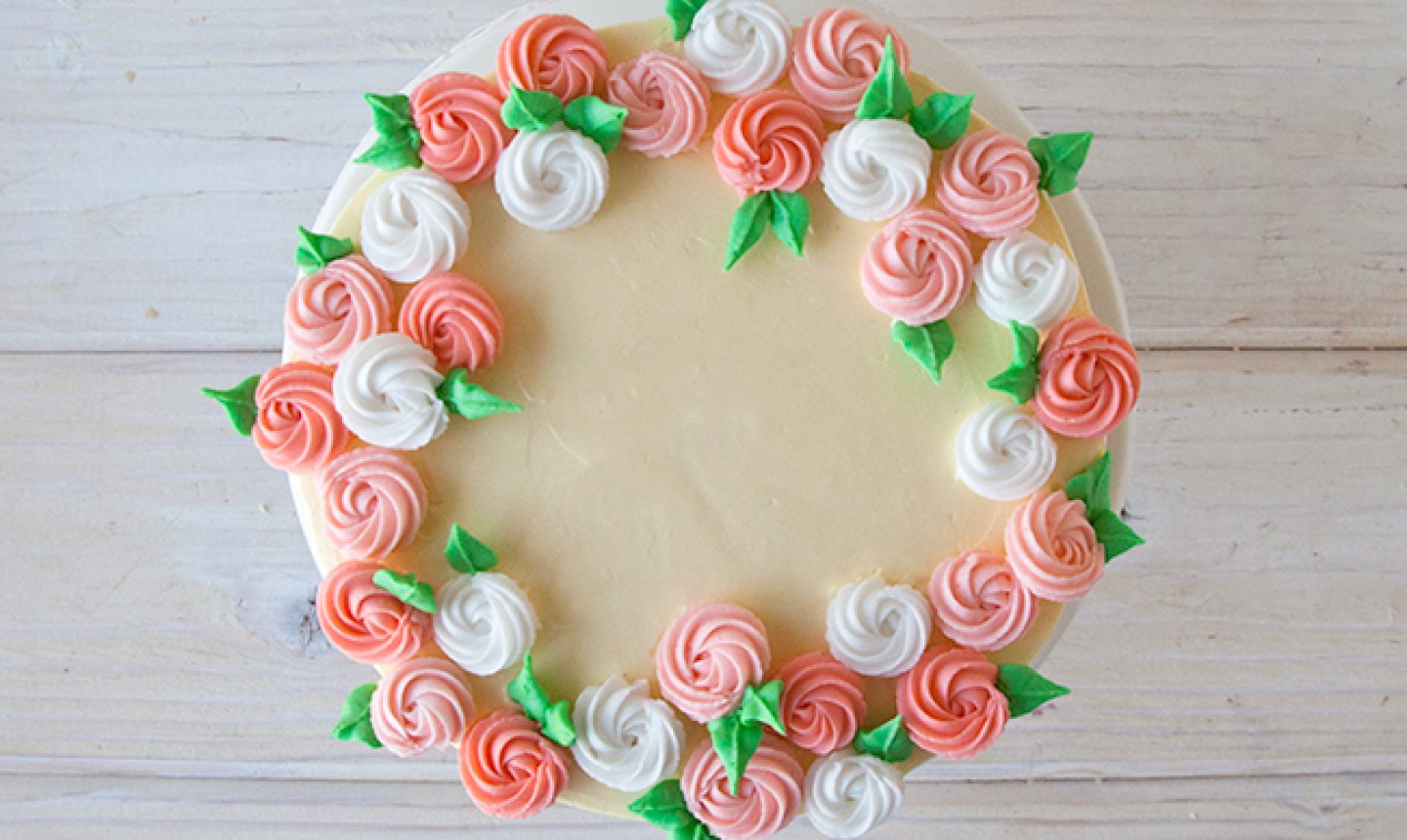 Pink and white piped rosettes on white cake