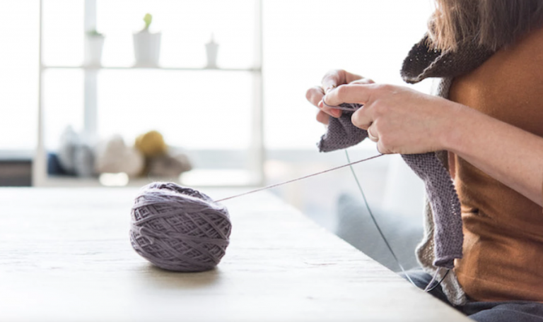 woman knitting from purple yarn