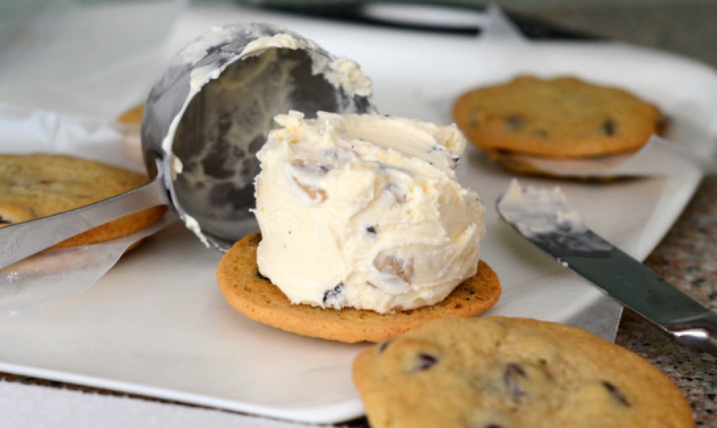 placing ice cream on chocolate chip cookie