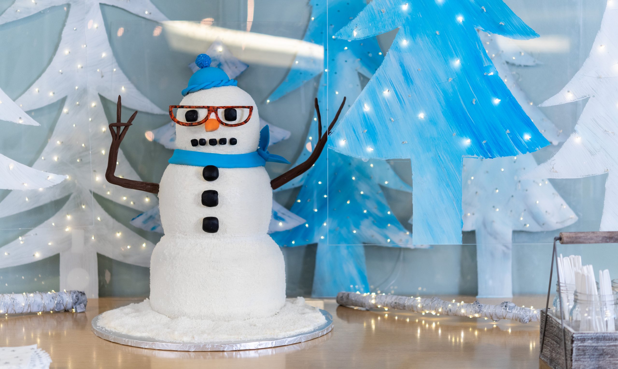 three tiered snowman cake with glasses a hat and scarf