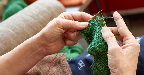 Person knitting with green yarn