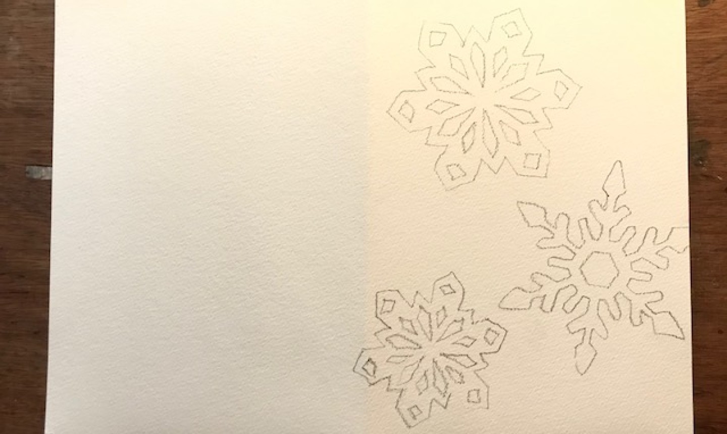 watercolor paper with snowflakes drawn in graphite