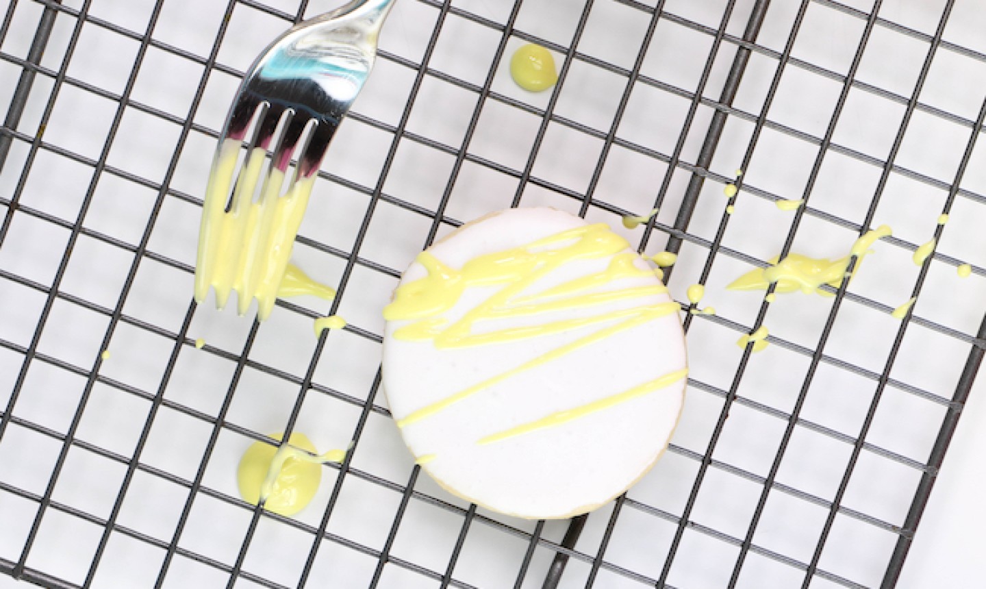 drizzling yellow royal icing on a cookie