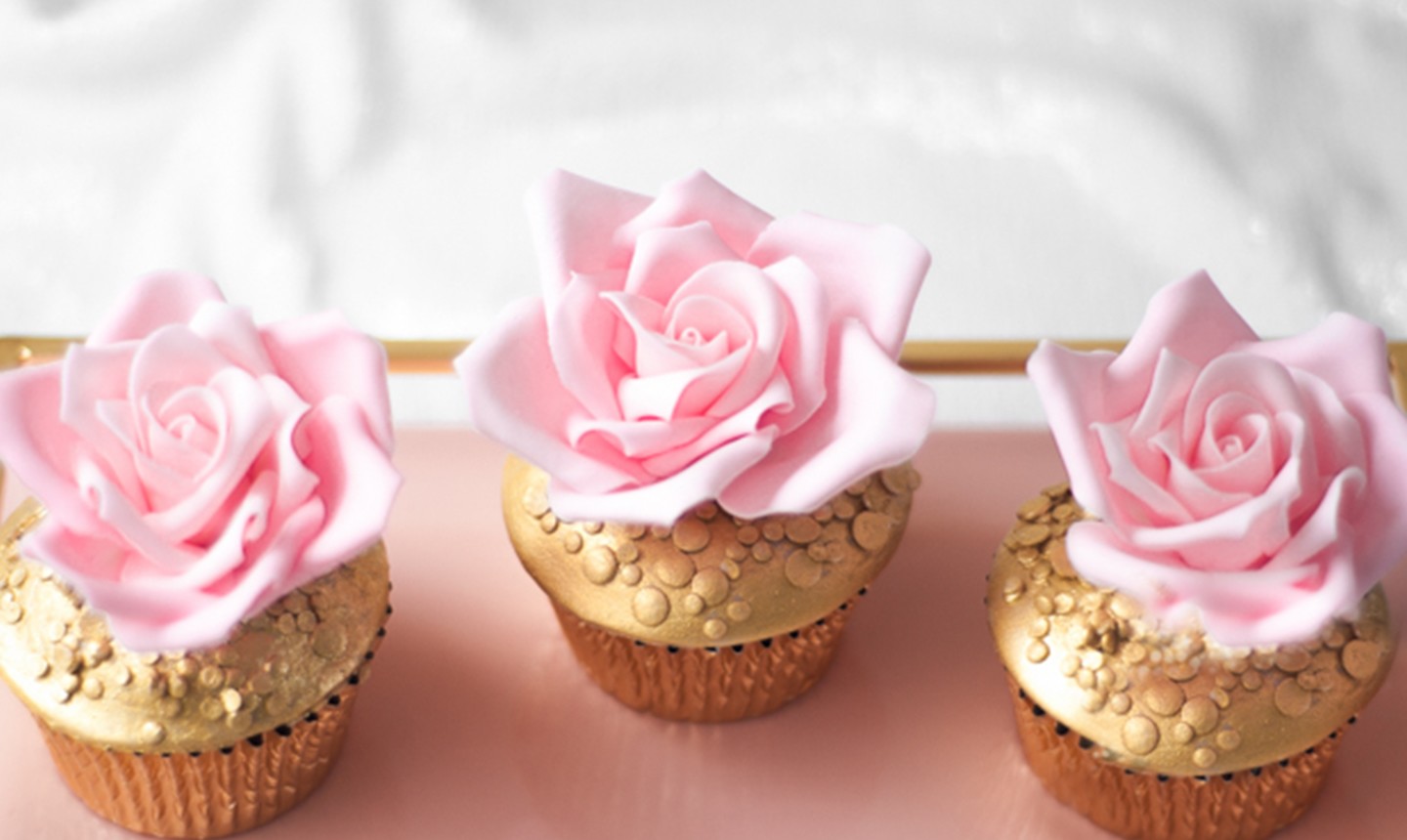 three cupcakes decorated with pink roses