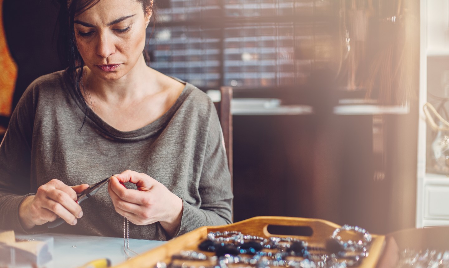 Jewelry maker woman working in her store. 