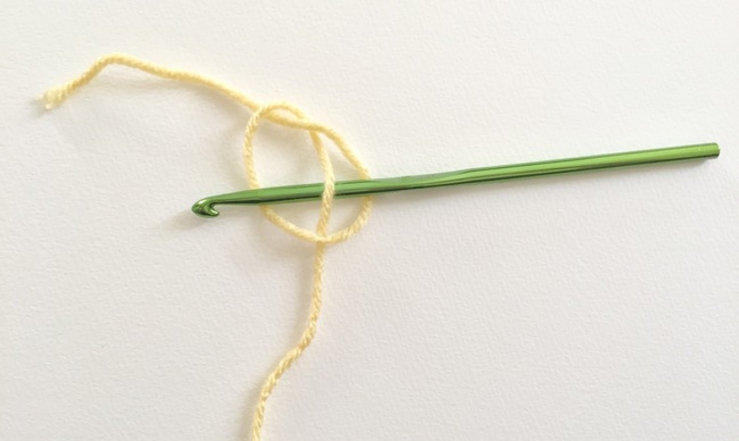 Piece of yellow yarn knotted with green hook