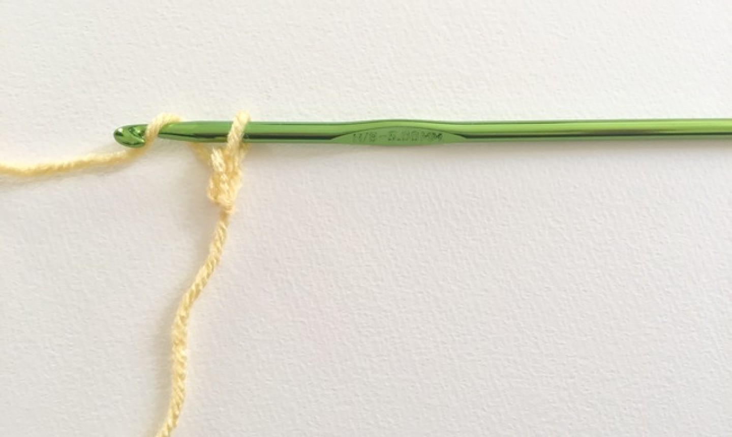 Yellow yarn knotted around green hook