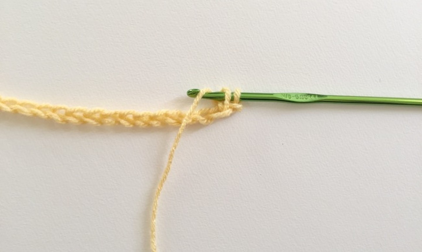 Chain of yellow yarn with green hook