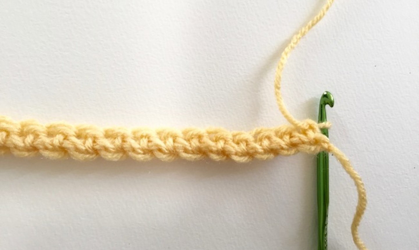 Chain of yellow yarn with green hook