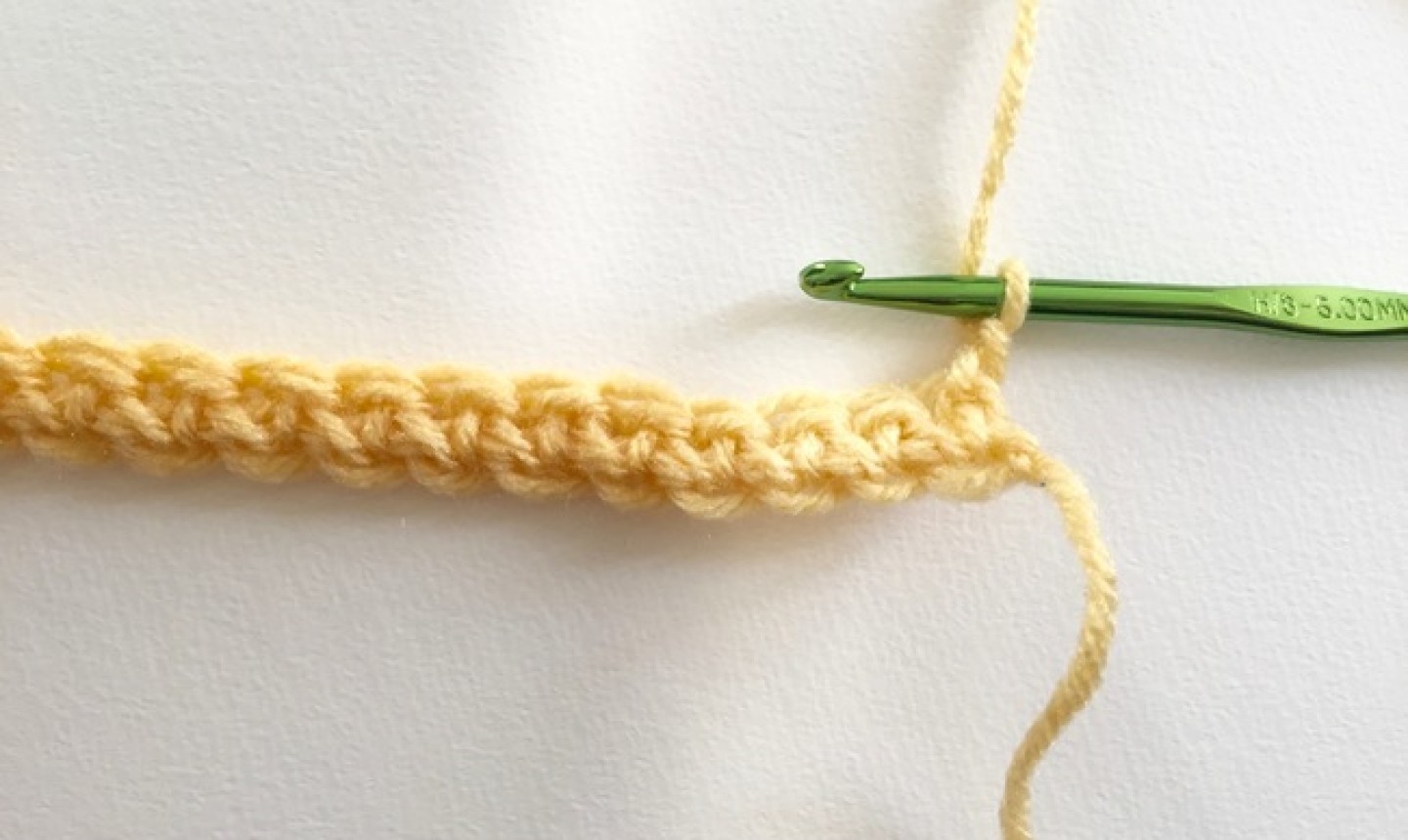 Chain of yellow yarn with green hook