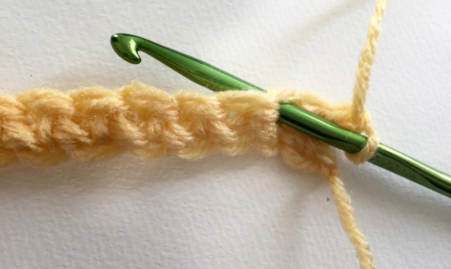 Chain of yellow yarn with green hook