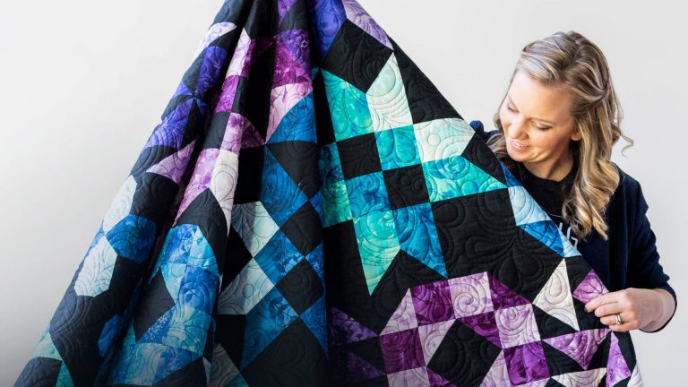 Woman holding up a quilt