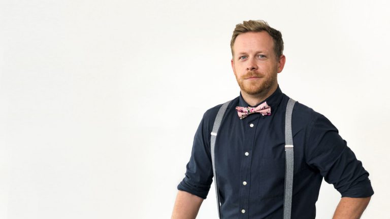 Man in a bow tie and suspenders smiling for the camera