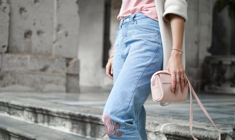Person in jeans holding a pink purse