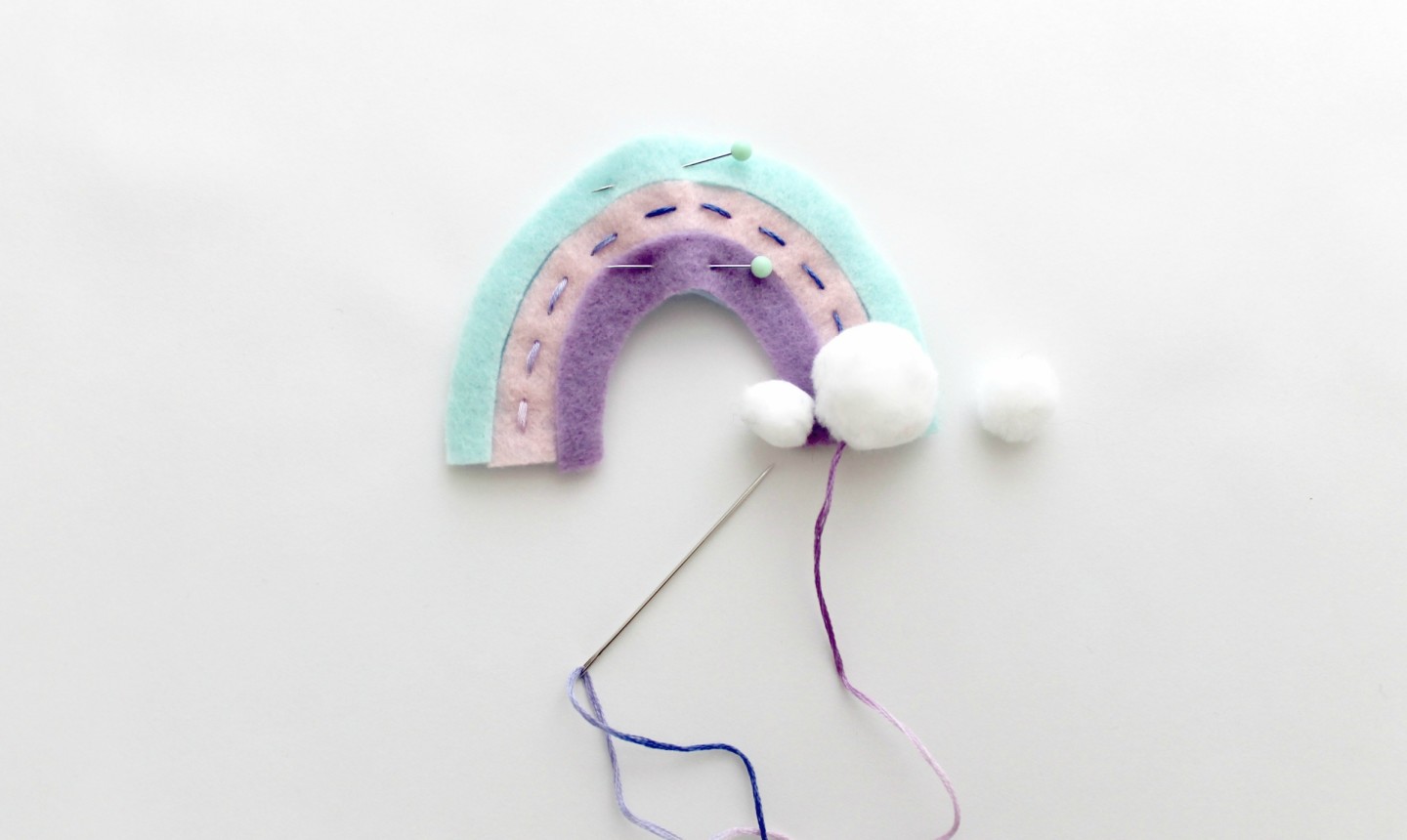 stitching clouds onto rainbow felt ornament