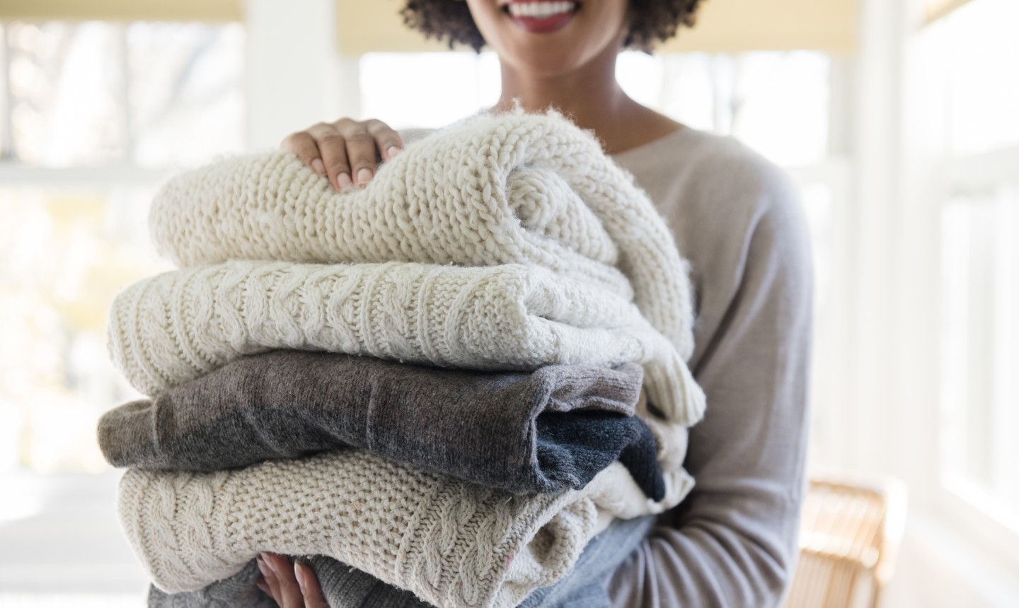 woman holding folded sweaters