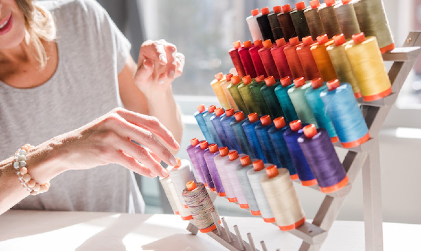 woman choosing thread from a thread stand