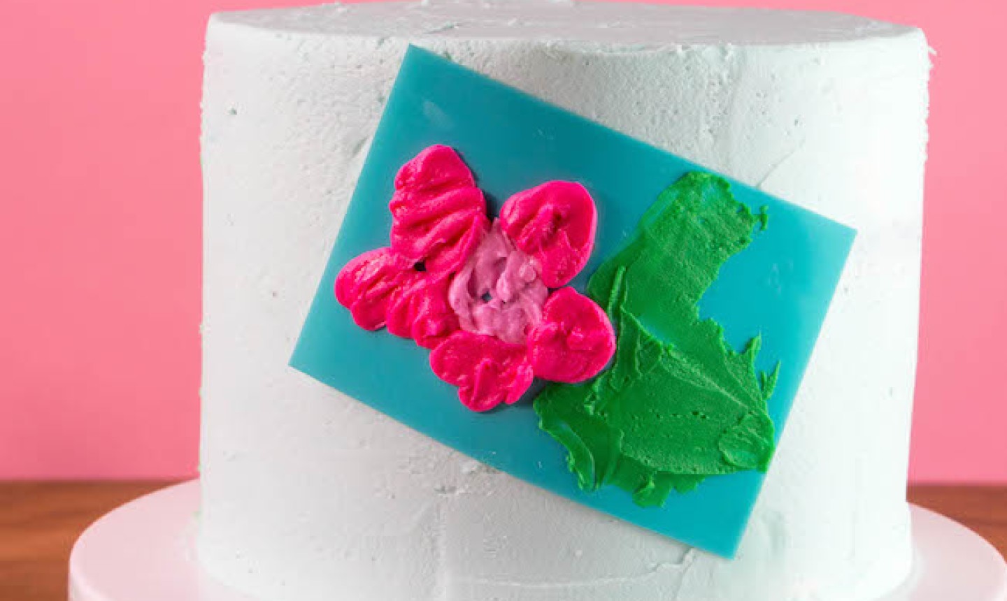 stenciling pink flower onto cake