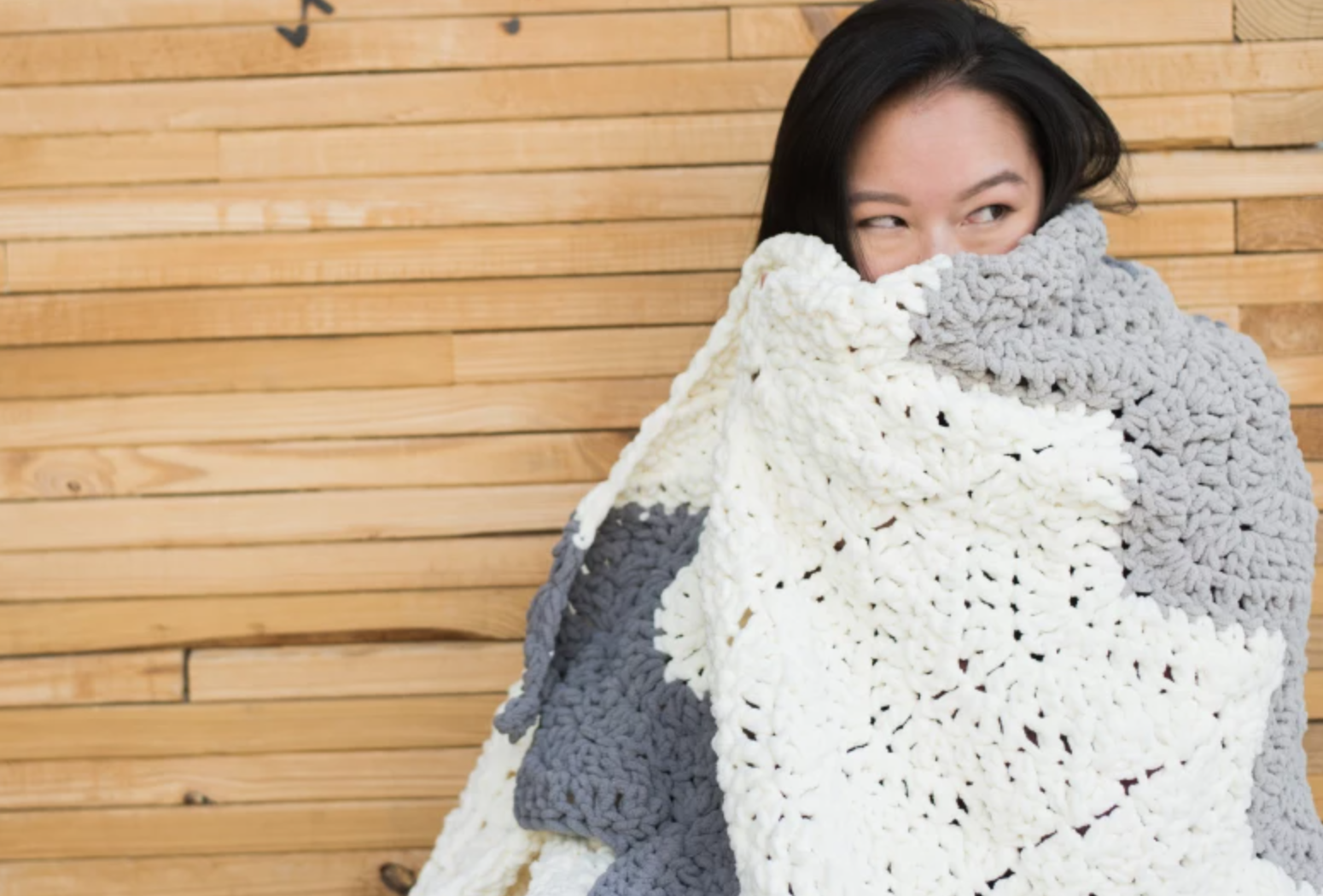 woman wrapped in crochet gray and white blanket