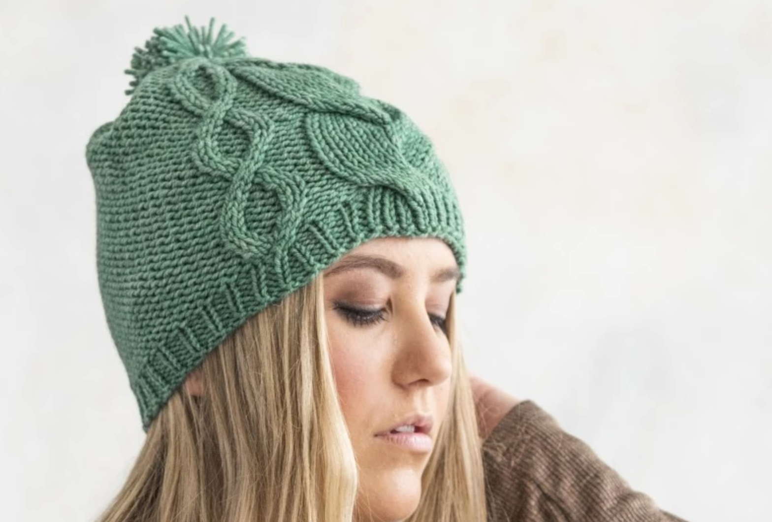 woman wearing green cabled knit hat