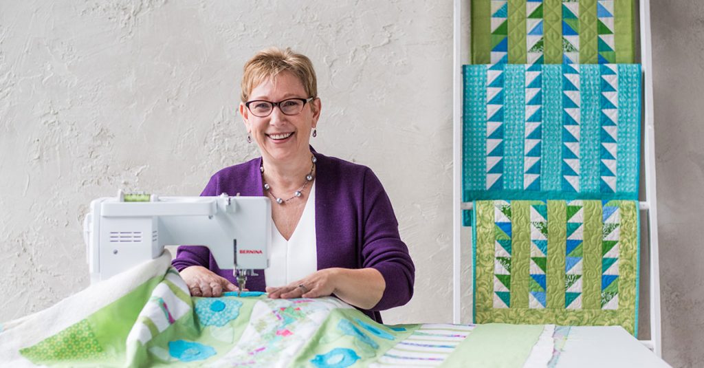 Woman sewing a quilt and smiling