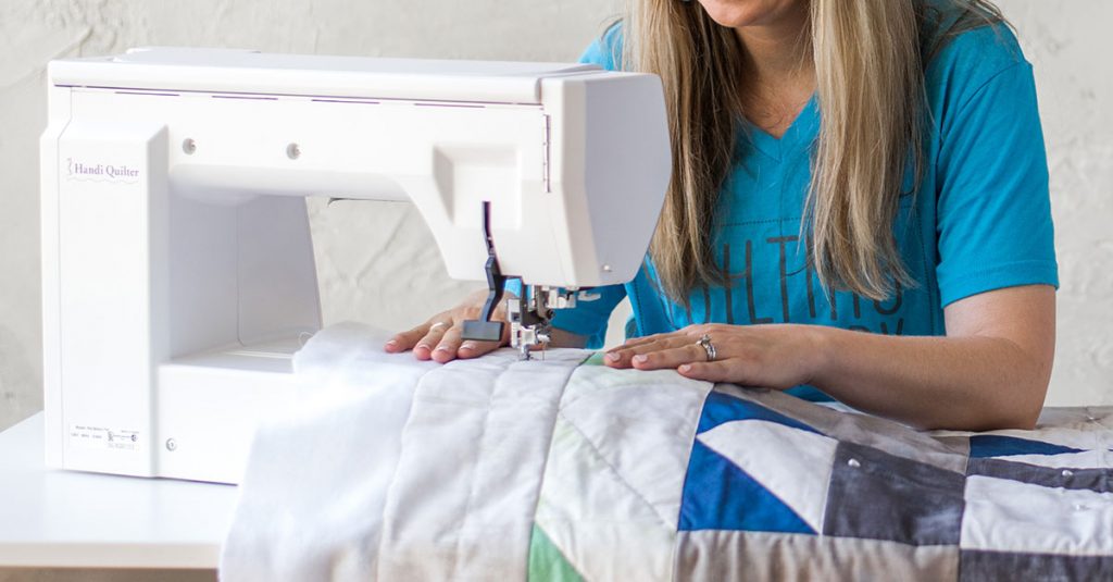 Woman in a blue shirt sewing a quilt