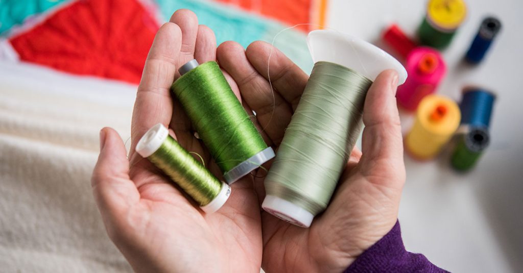 Person holding shades of green thread