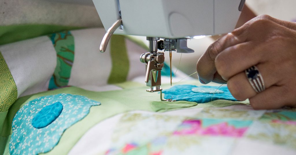Sewing a scrap fabric flower to a quilt
