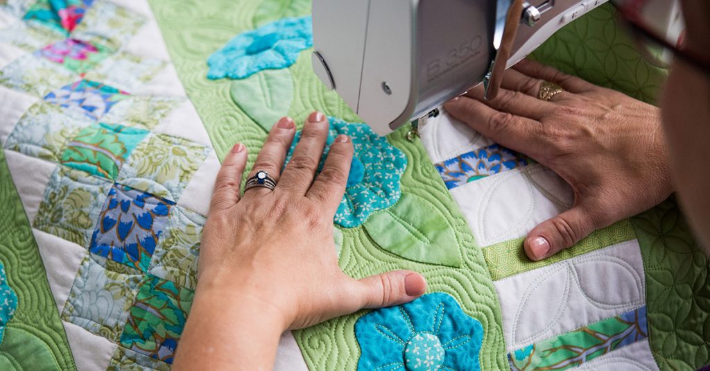 Woman sewing edge of a flower quilt