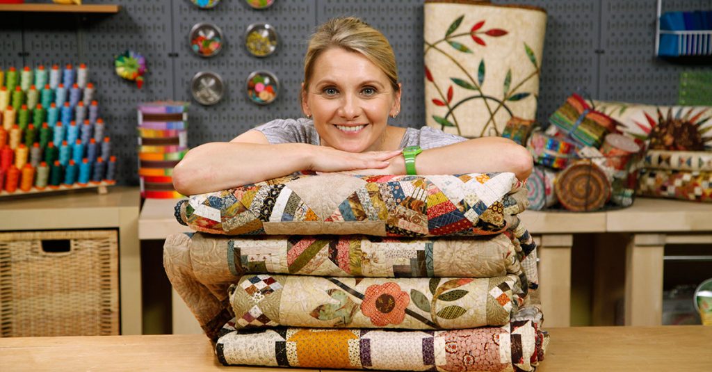 Woman smiling and posing on top of folded quilts