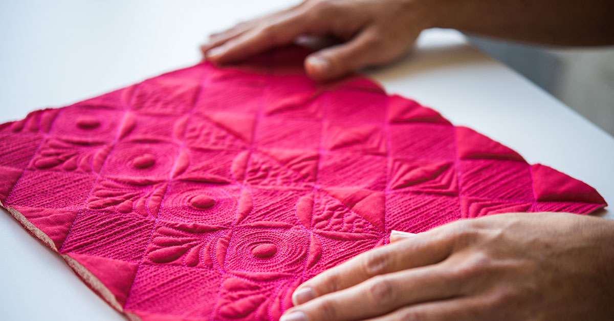 Person holding bright pink quilted square