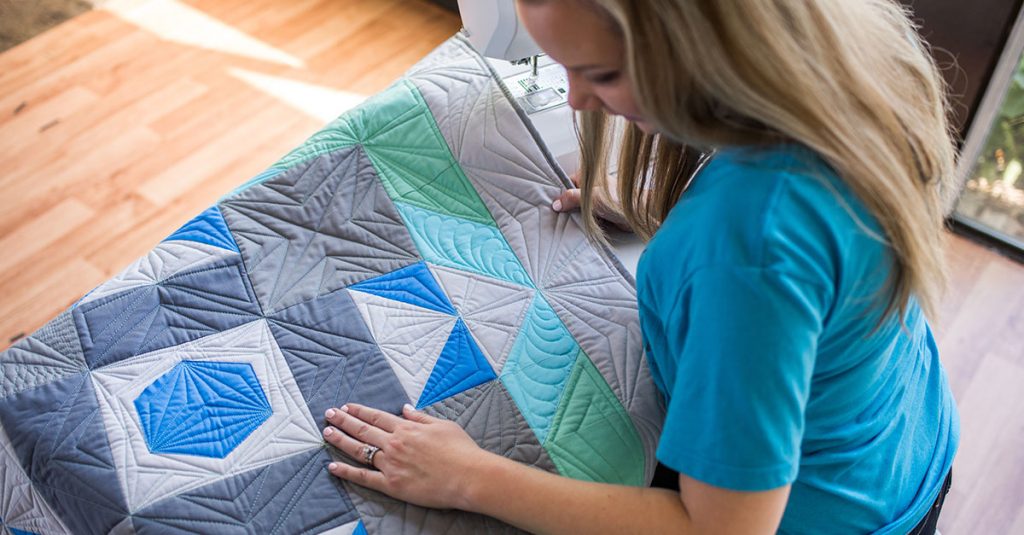 Woman looking at quilt with shades of blue and green
