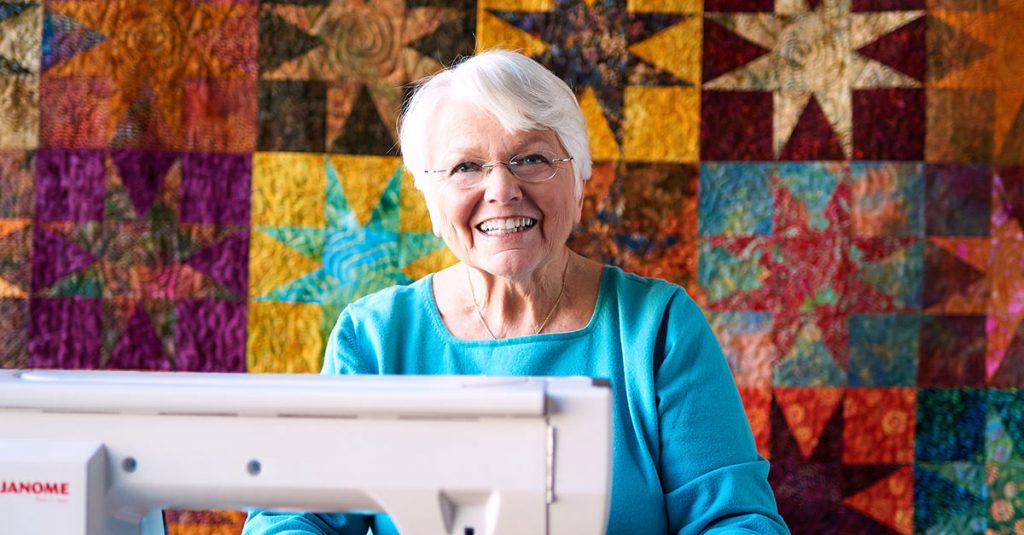 Woman smiling in front of a quilt background