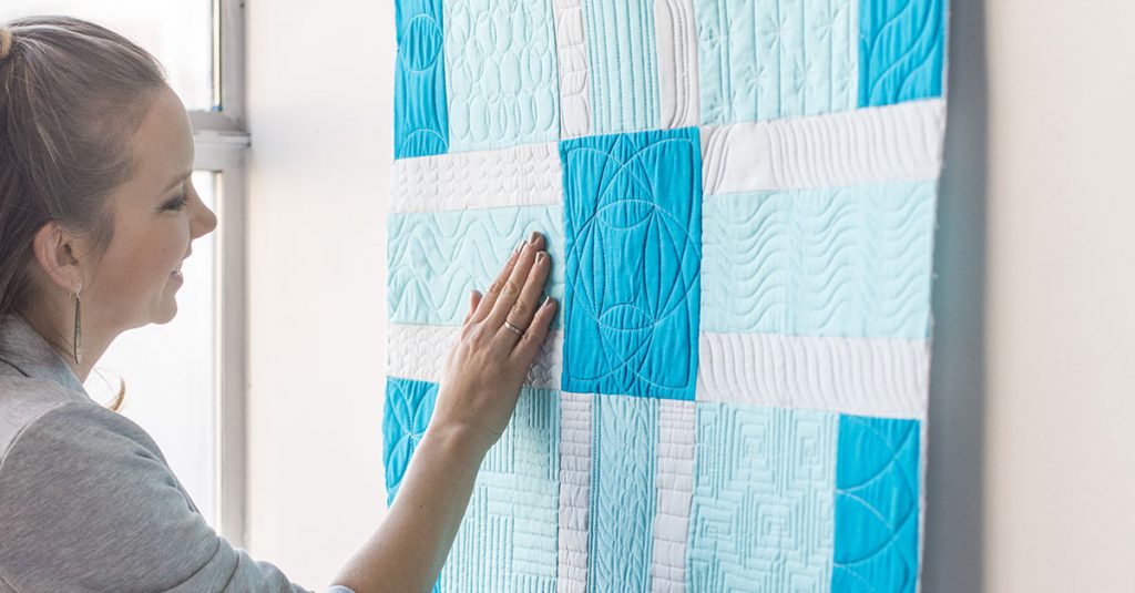 Person touching a blue and white quilt