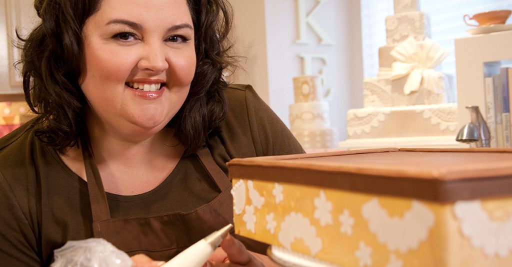 Woman piping frosting designs on a cake