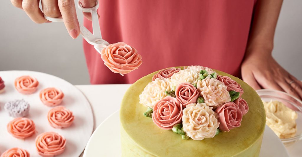 Adding buttercream flowers to a cake