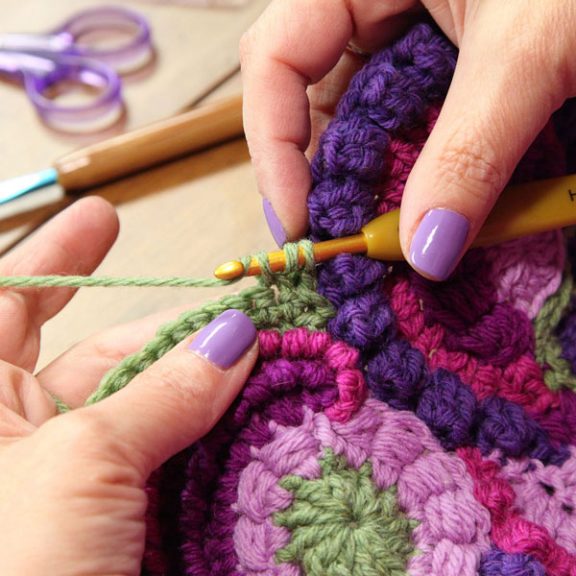 Crocheting a green edge around colorful circles