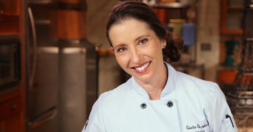Woman in a pastry chef jacket smiling at camera