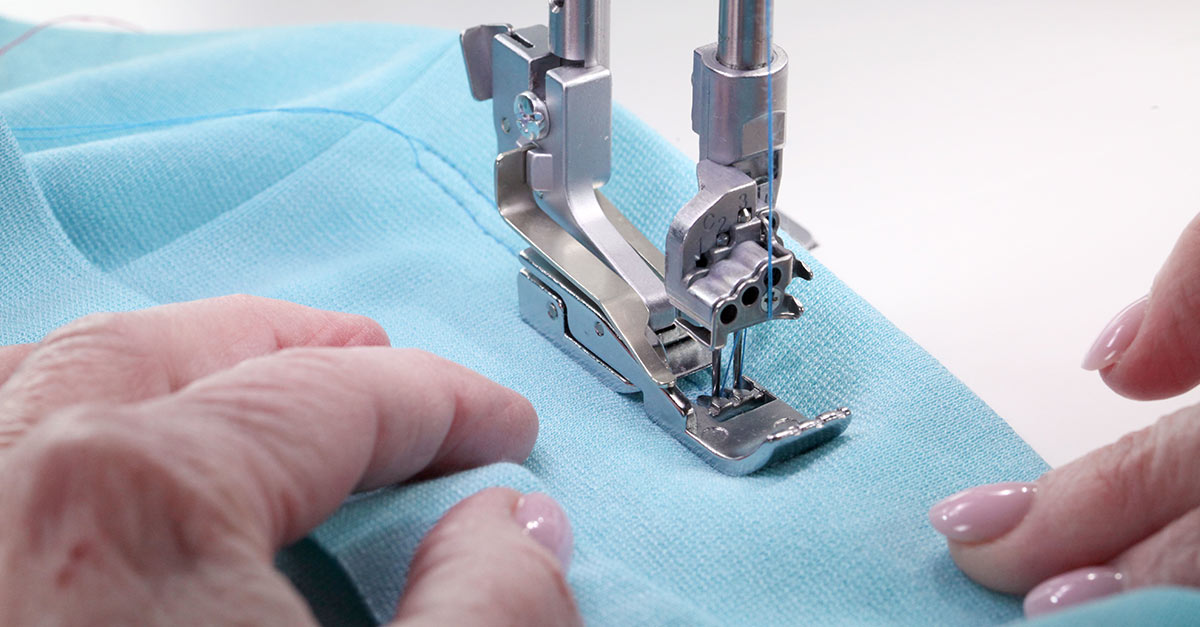 Sewing machine foot sewing on blue fabric