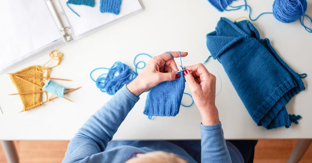 Person knitting with blue crochet
