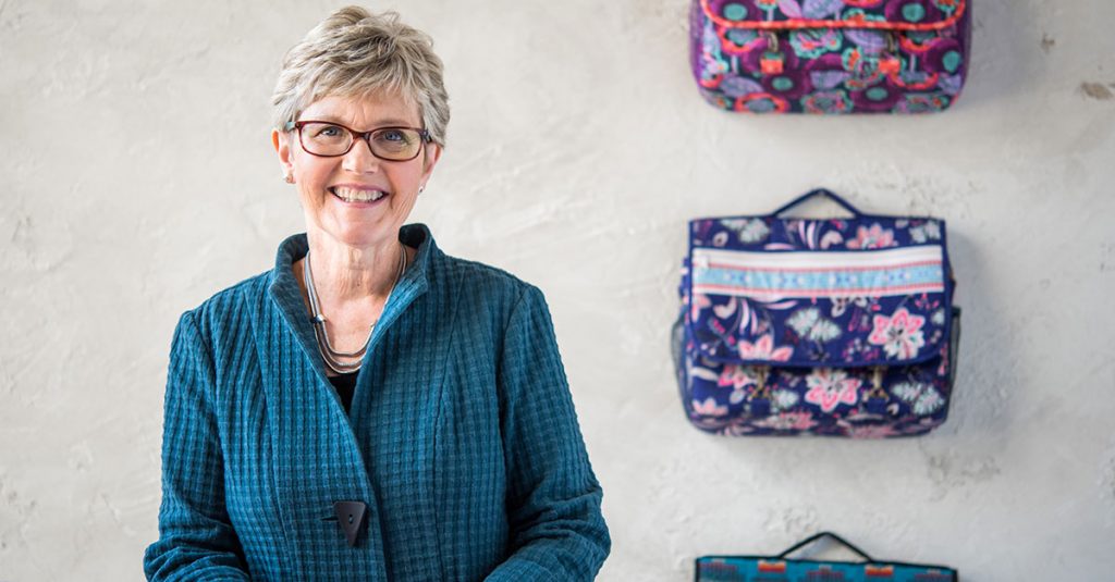 Woman posing in front of patterned messenger bags